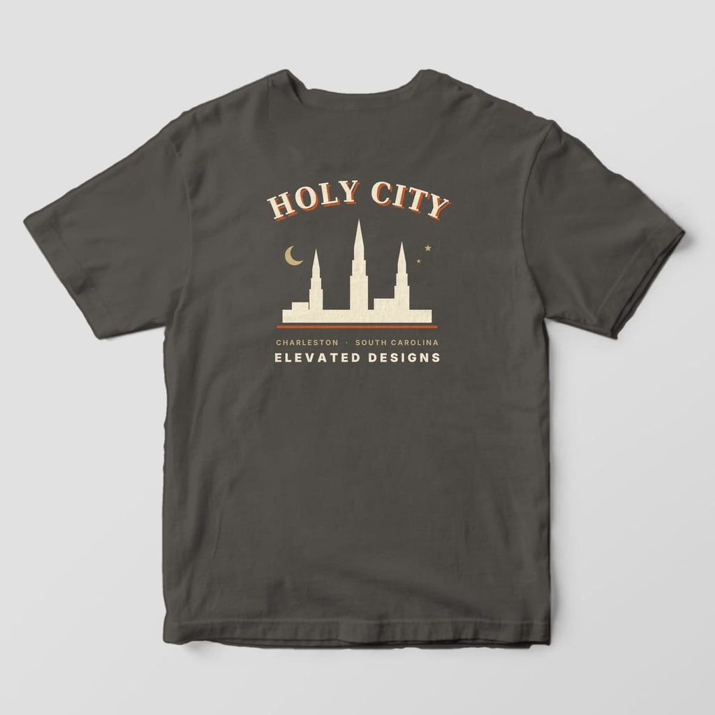Back of a Pepper Comfort Colors 1717 tee with HOLY CITY arched over a cream skyline of three church steeples with a gold crescent moon and two stars, then CHARLESTON · SOUTH CAROLINA and ELEVATED DESIGNS.