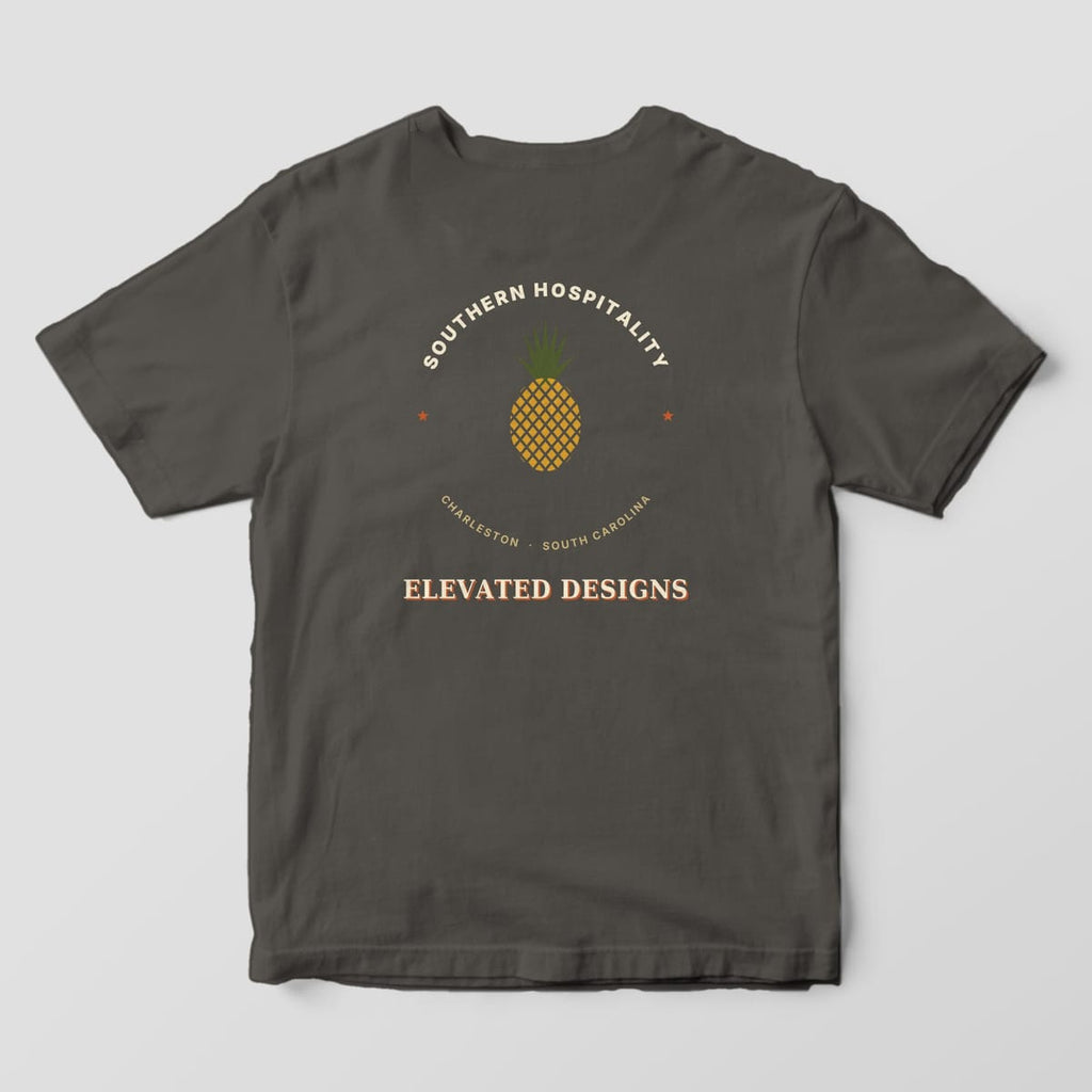 Back of a Pepper Comfort Colors 1717 tee with SOUTHERN HOSPITALITY arched over a gold pineapple with an olive crown, two rust stars, CHARLESTON · SOUTH CAROLINA and ELEVATED DESIGNS.