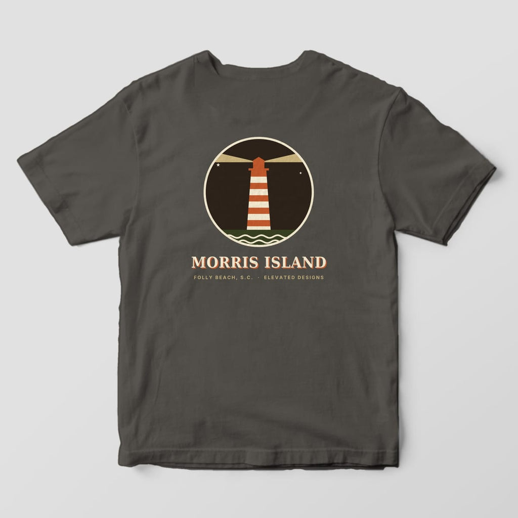 Back of a Pepper Comfort Colors 1717 tee with a round dark night badge of a rust-and-cream striped lighthouse with tan light beams and waves, above MORRIS ISLAND and FOLLY BEACH, S.C. · ELEVATED DESIGNS.