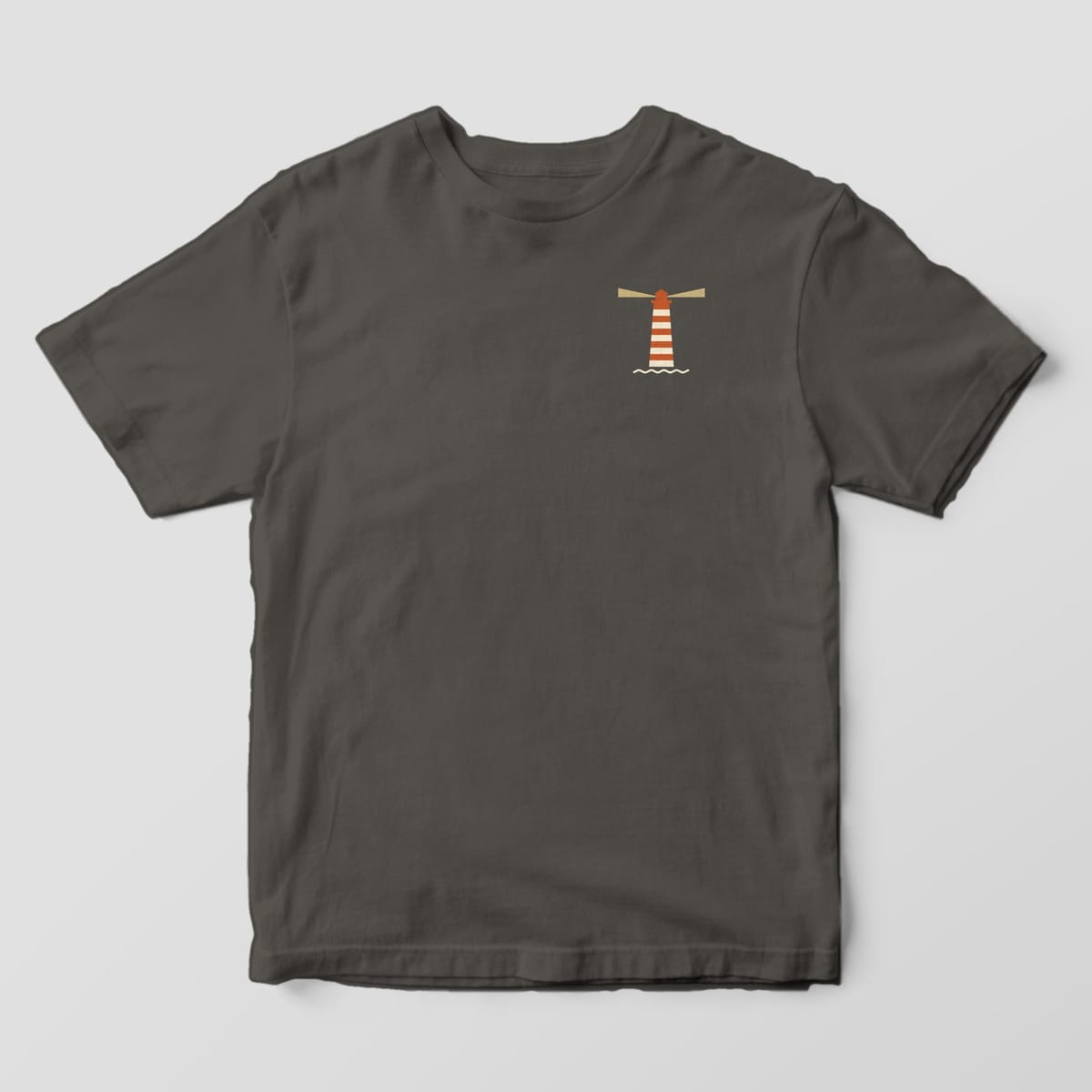 Front of a Pepper Comfort Colors 1717 tee with a small left-chest rust-and-cream striped lighthouse with tan light beams above a wavy cream line.