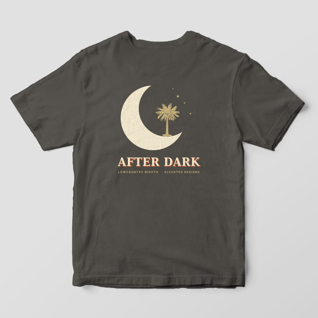 Back of a Pepper Comfort Colors 1717 tee with a large cream crescent moon cradling a gold palmetto tree with four small stars, above AFTER DARK and LOWCOUNTRY NIGHTS · ELEVATED DESIGNS.