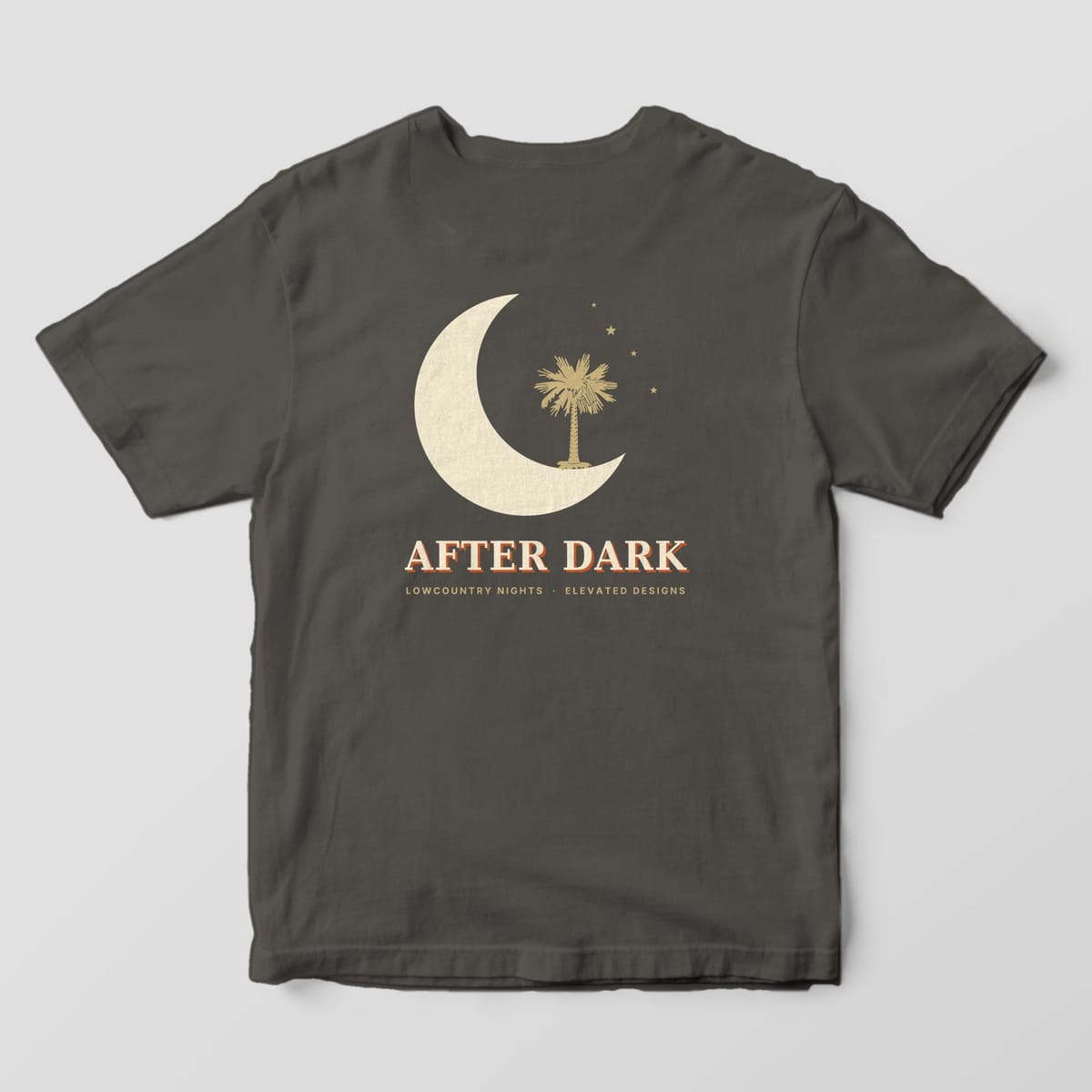 Back of a Pepper Comfort Colors 1717 tee with a large cream crescent moon cradling a gold palmetto tree with four small stars, above AFTER DARK and LOWCOUNTRY NIGHTS · ELEVATED DESIGNS.