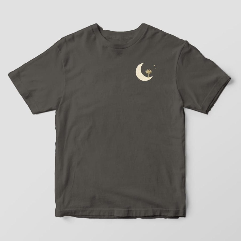 Front of a Pepper Comfort Colors 1717 tee with a small left-chest cream crescent moon with a gold palmetto tree and two stars.