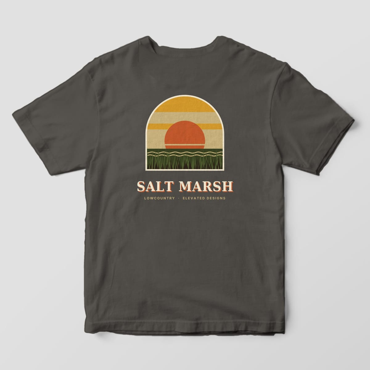Back of a Pepper Comfort Colors 1717 tee with an arched window scene of an orange sun setting over wavy water and tall green marsh grass under gold and tan bands, above SALT MARSH and LOWCOUNTRY · ELEVATED DESIGNS.