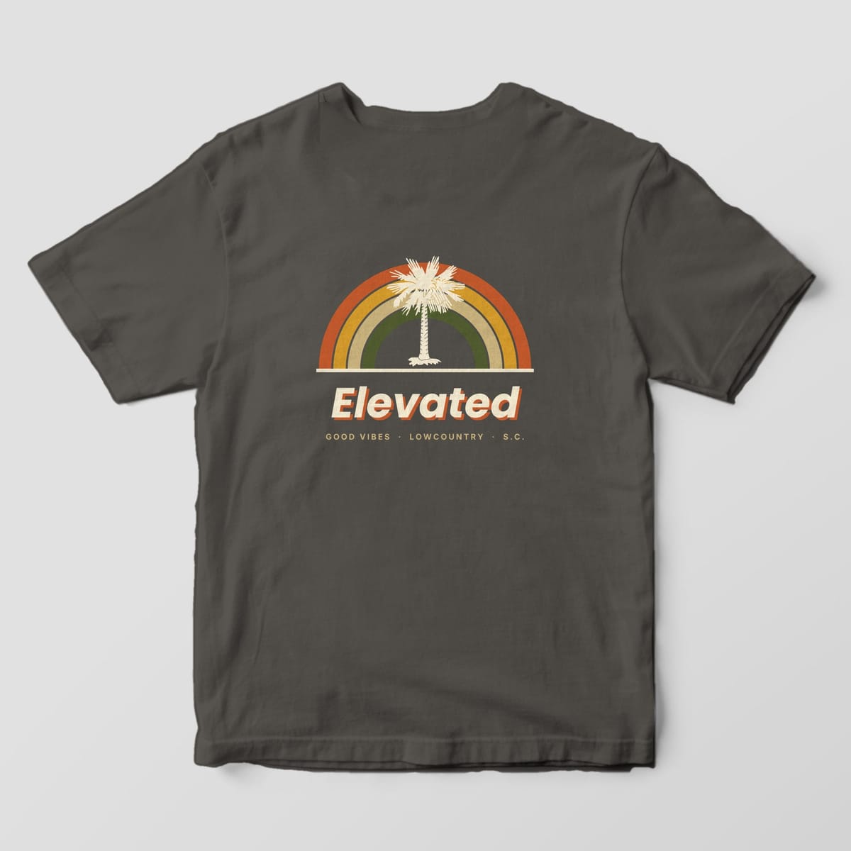 Back of a Pepper Comfort Colors 1717 tee with four retro rainbow arcs in rust, gold, tan and olive around a cream palmetto tree, above Elevated and GOOD VIBES · LOWCOUNTRY · S.C.