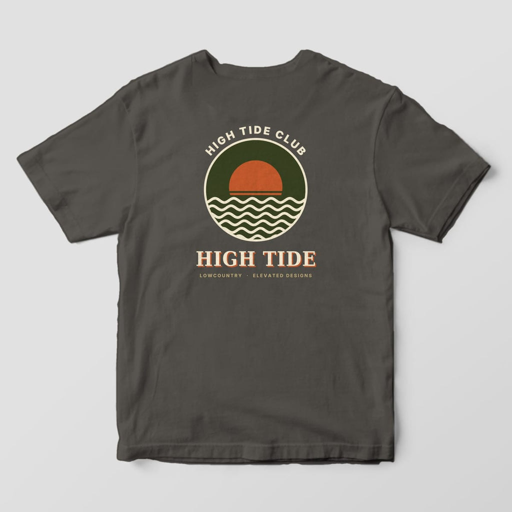 Back of a Pepper Comfort Colors 1717 tee with HIGH TIDE CLUB arched over a round olive badge with a rust sun and cream waves, above HIGH TIDE and LOWCOUNTRY · ELEVATED DESIGNS.