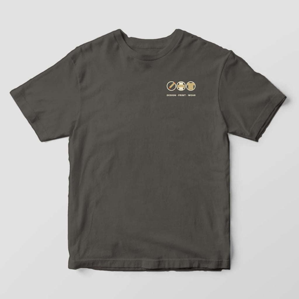 Front of a Pepper Comfort Colors 1717 tee with a small left-chest row of a pencil, printer and t-shirt icon in cream circles above DESIGN · PRINT · WEAR.