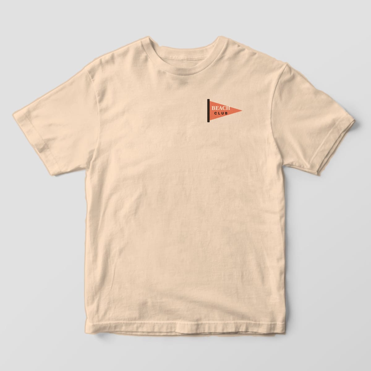 Front of an Ivory Comfort Colors 1717 tee with a small left-chest coral pennant flag on a dark pole reading BEACH CLUB.