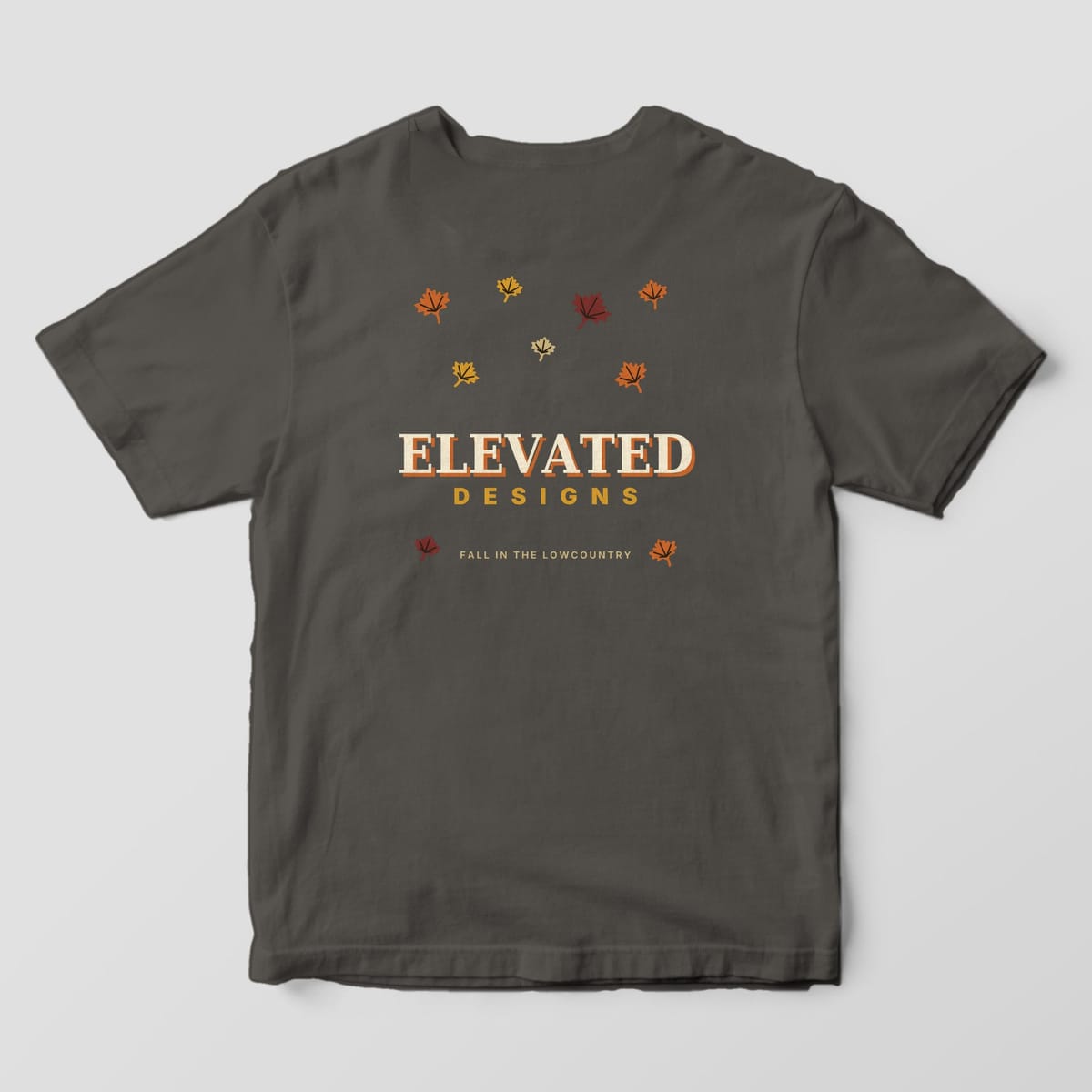 Back of a Pepper Comfort Colors 1717 tee with scattered maple leaves in rust, gold, maroon and tan around ELEVATED DESIGNS and FALL IN THE LOWCOUNTRY.