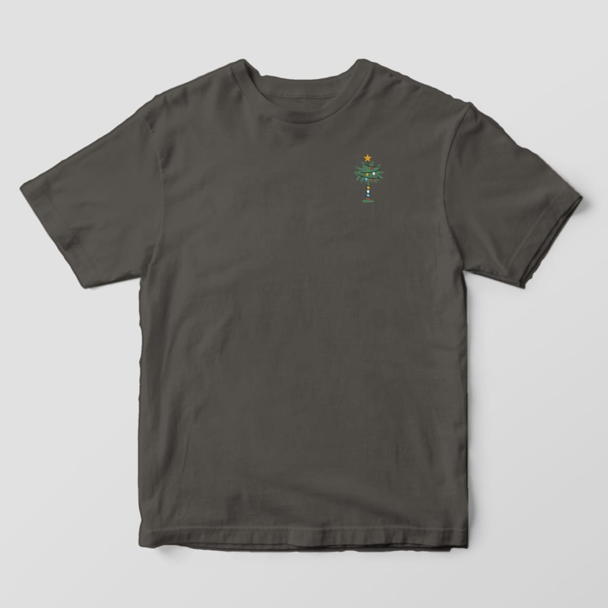 Front of a Pepper Comfort Colors 1717 tee with a small left-chest green palmetto wrapped in colorful string lights with a gold star on top.