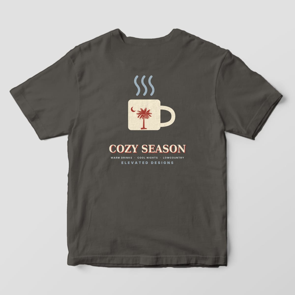 Back of a Pepper Comfort Colors 1717 tee with a cream mug with a red palmetto and crescent moon under three steam lines, above COZY SEASON and WARM DRINKS · COOL NIGHTS · LOWCOUNTRY.