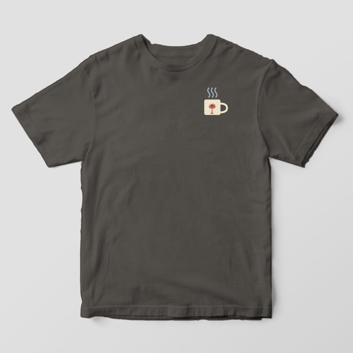 Front of a Pepper Comfort Colors 1717 tee with a small left-chest cream mug with a red palmetto and three wavy steam lines.
