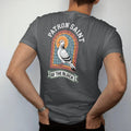 Man wearing a Graphite tee, seen from the back: a haloed city pigeon in a stained-glass frame under the words Patron Saint and over a banner reading Of The Block, in bone white, orange, green and yellow.