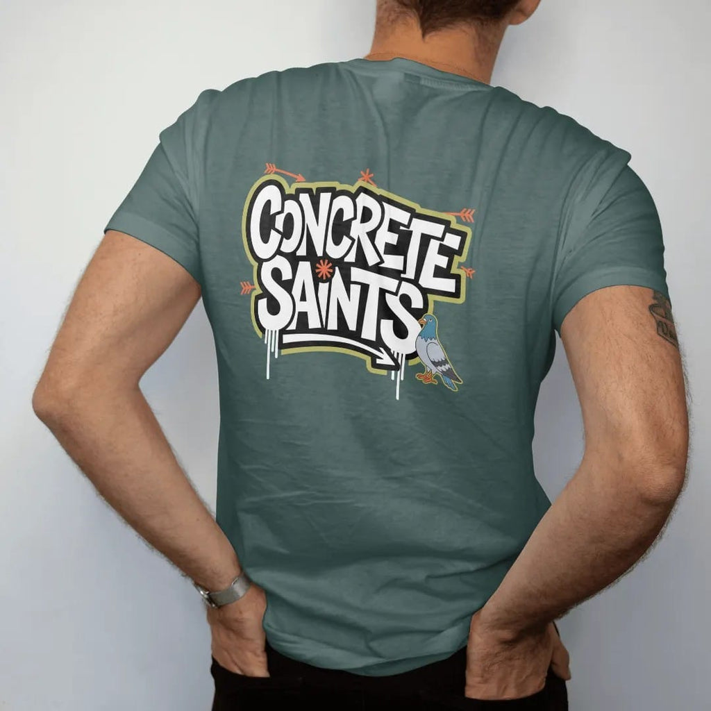 Man wearing a Blue Spruce tee, seen from the back: a wildstyle graffiti piece spelling Concrete Saints with arrows, drips and a haloed pigeon character, in orange, green, yellow and bone white.