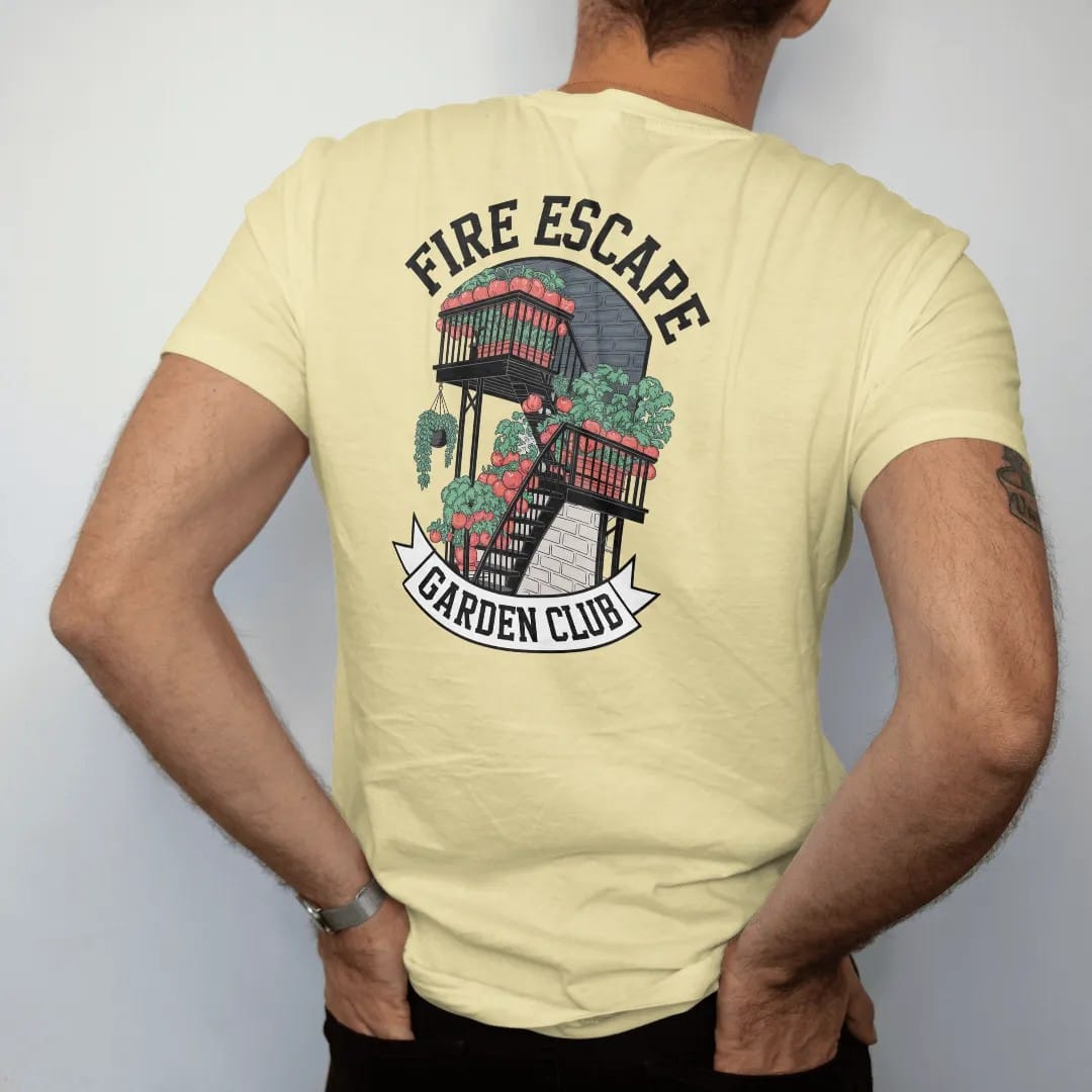 Man wearing a Butter tee, seen from the back: a fire escape crowded with potted tomatoes and herbs under Fire Escape and over a Garden Club banner, in charcoal, brick red, green and navy.