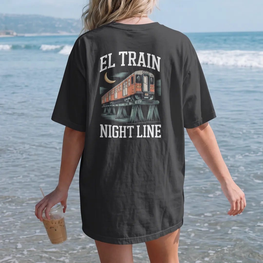 Woman on the beach in a Black tee, back view: an elevated train with lit windows crossing steel trestles under a crescent moon, with El Train above and Night Line below, in yellow, bone white, orange and green.