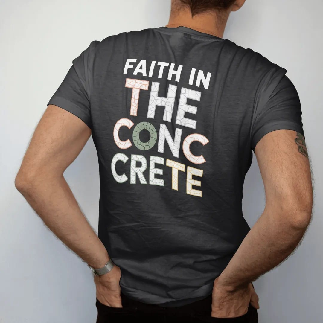 Man wearing a Black tee, seen from the back: large cracked-concrete letters reading The Concrete under small spaced Faith In with a halo over the first letter, in bone white, orange and green.