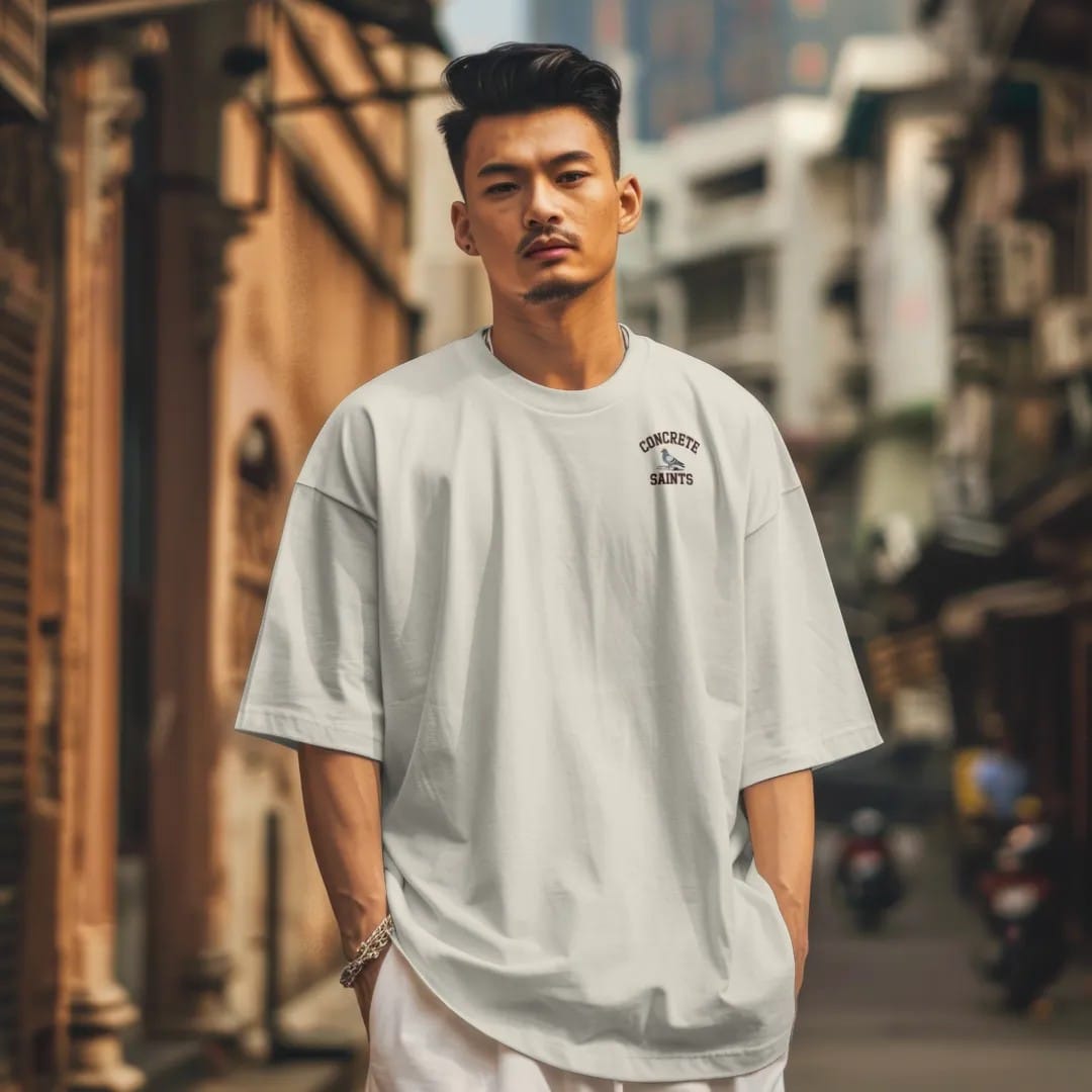 Man in a Ivory tee on a city street, with the small Concrete Saints logo on the left chest.