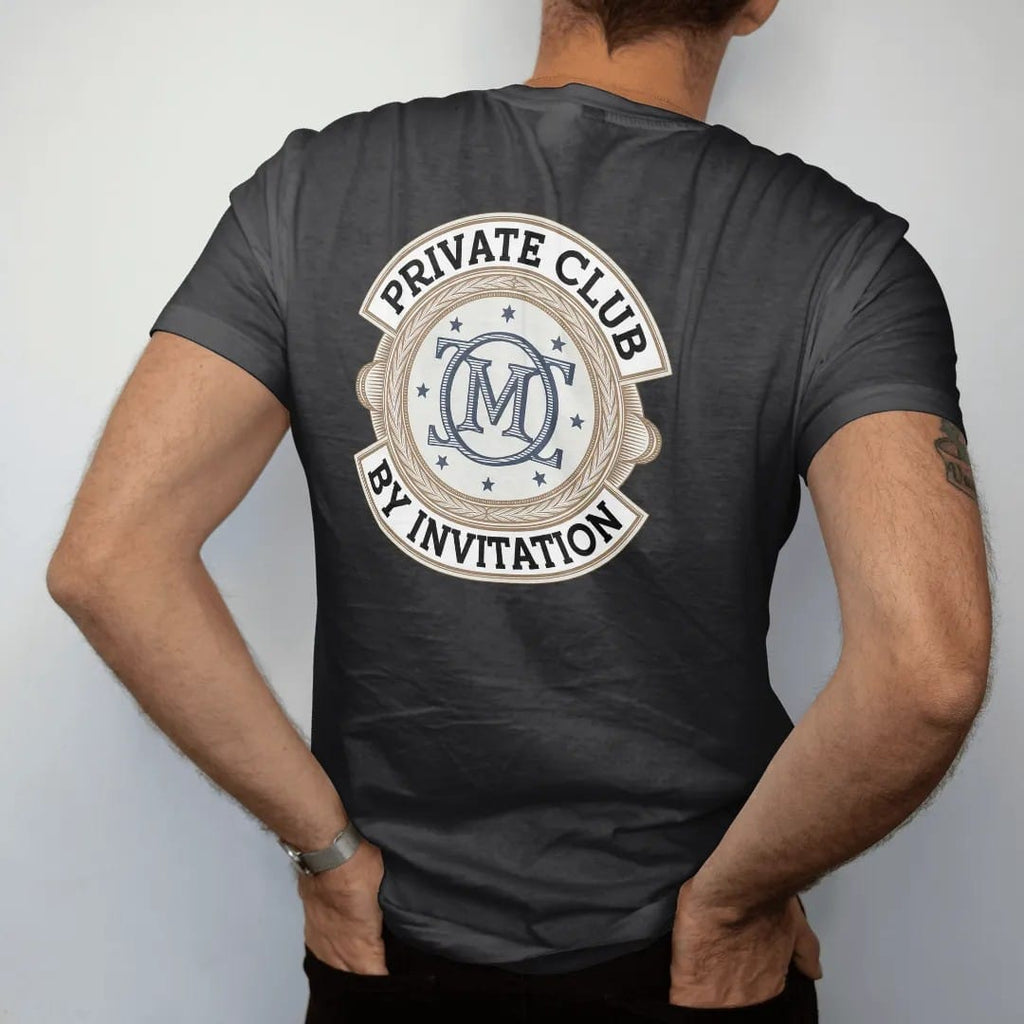Man wearing a Black tee, seen from the back: an interlocking serif monogram in a double ring with tiny stars, ringed by Private Club and By Invitation, as a fine engraving in navy and antique gold.
