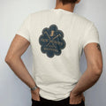 Man wearing a Ivory tee, seen from the back: a small top hat and crossed cane between New Money and Old Manners, as a fine engraving in navy and antique gold.