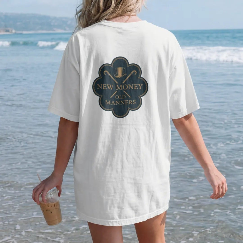 Woman on the beach in a White tee, back view: a small top hat and crossed cane between New Money and Old Manners, as a fine engraving in navy and antique gold.