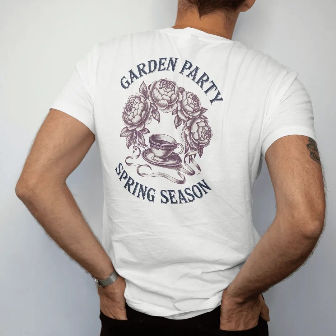 Man wearing a White tee, seen from the back: a wreath of peonies and roses with ribbons around a teacup, with Garden Party in script and Spring Season below, as a fine engraving in navy and antique gold.
