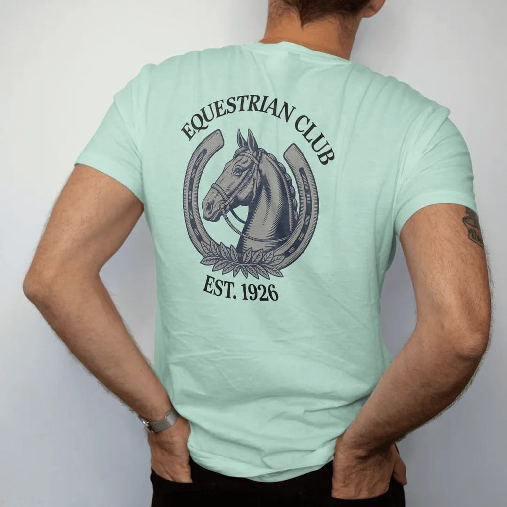 Man wearing a Chalky Mint tee, seen from the back: a horse head in profile inside a horseshoe with a bridle and laurel, under Equestrian Club and Est. 1926, as a fine engraving in navy and antique gold.