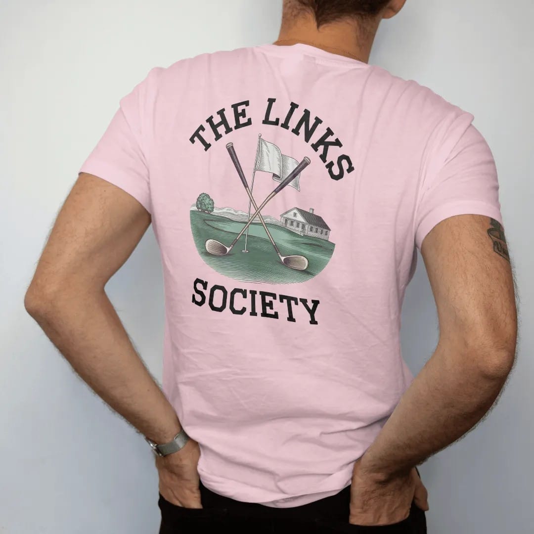 Man wearing a Blossom tee, seen from the back: crossed vintage golf clubs over a flag and green with a clubhouse, under The Links and Society, as a fine engraving in navy and antique gold.