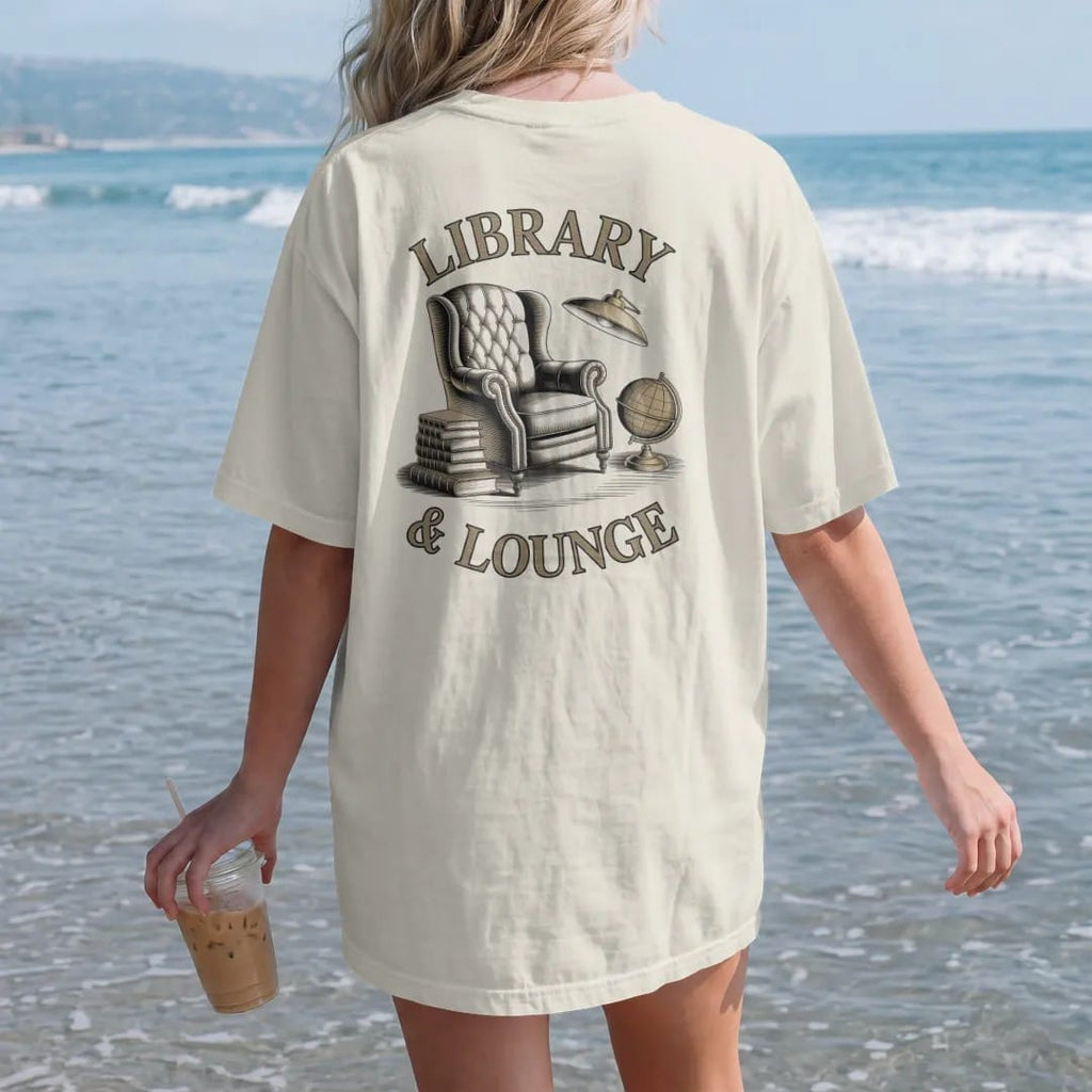 Woman on the beach in a Ivory tee, back view: a leather armchair with books, a brass lamp and a globe under Library and & Lounge, as a fine engraving in cream and champagne gold.