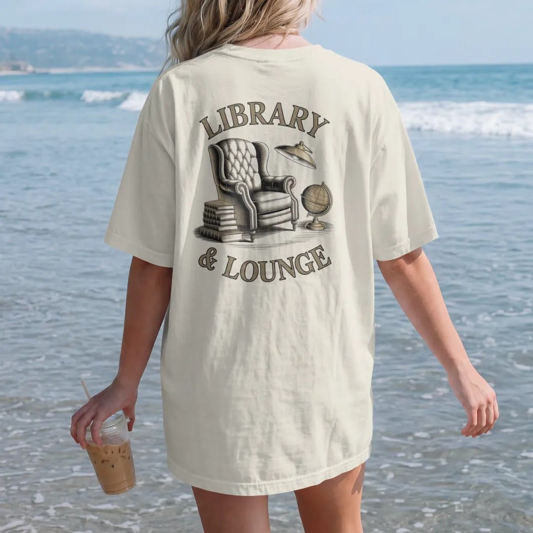 Woman on the beach in a Ivory tee, back view: a leather armchair with books, a brass lamp and a globe under Library and & Lounge, as a fine engraving in cream and champagne gold.