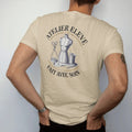 Man wearing a Sandstone tee, seen from the back: a dress form, scissors, tape measure and thread spool under Atelier Elevé and the script Fait Avec Soin, as a fine engraving in navy and antique gold.