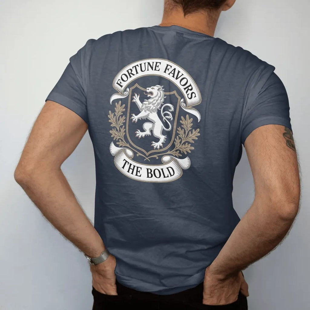 Man wearing a Midnight tee, seen from the back: a rampant lion on a shield with oak leaves, Fortune Favors arched above and The Bold on a ribbon, as a fine engraving in cream and champagne gold.
