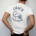 Man wearing a White tee, seen from the back: a swan gliding on still water with reeds and a reflection under Grace in script and Under Pressure, as a fine engraving in navy and antique gold.