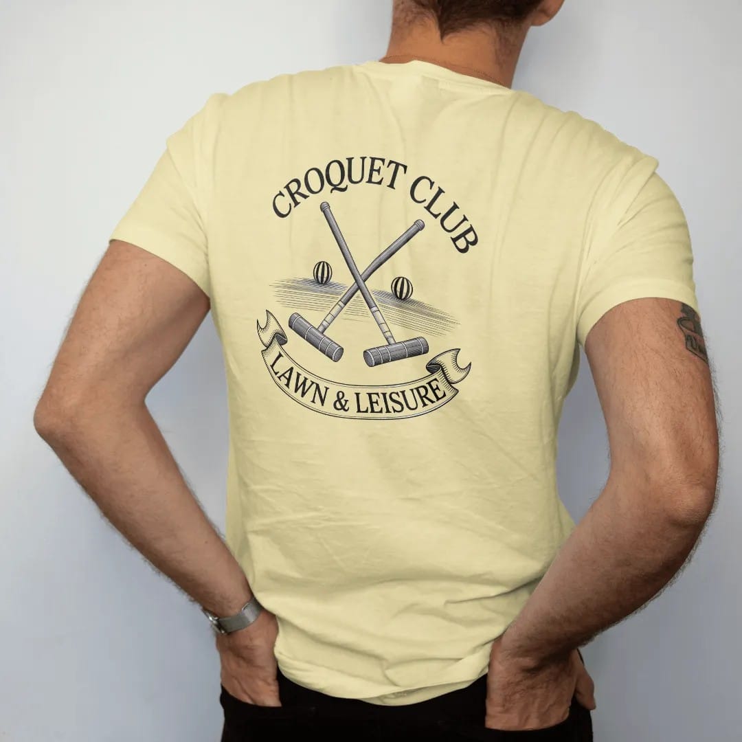 Man wearing a Butter tee, seen from the back: crossed croquet mallets with striped balls and a wicket on a lawn under Croquet Club and a Lawn & Leisure ribbon, as a fine engraving in navy and antique gold.