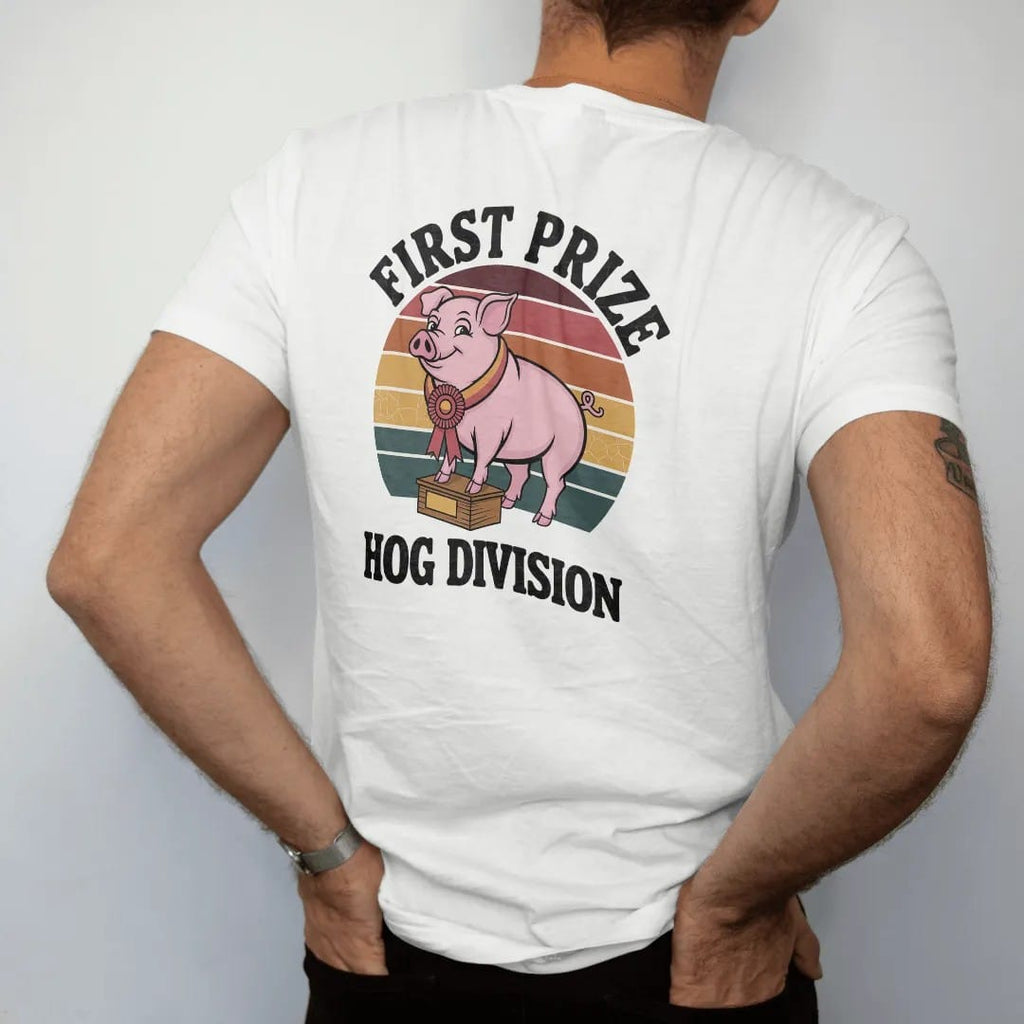 Man wearing a White tee, seen from the back: a proud cartoon pig wearing a rosette ribbon on a judging block, with "FIRST PRIZE" and "HOG DIVISION" in chunky 70s lettering and small 70s caps, printed in faded, cracked brown, rust red, mustard and…
