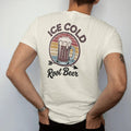 Man wearing a Ivory tee, seen from the back: a frosty root beer mug with spilling foam, with "ICE COLD" and "ROOT BEER" in chunky 70s lettering and brush script, printed in faded, cracked brown, rust red, mustard and dusty teal over faded sunset…
