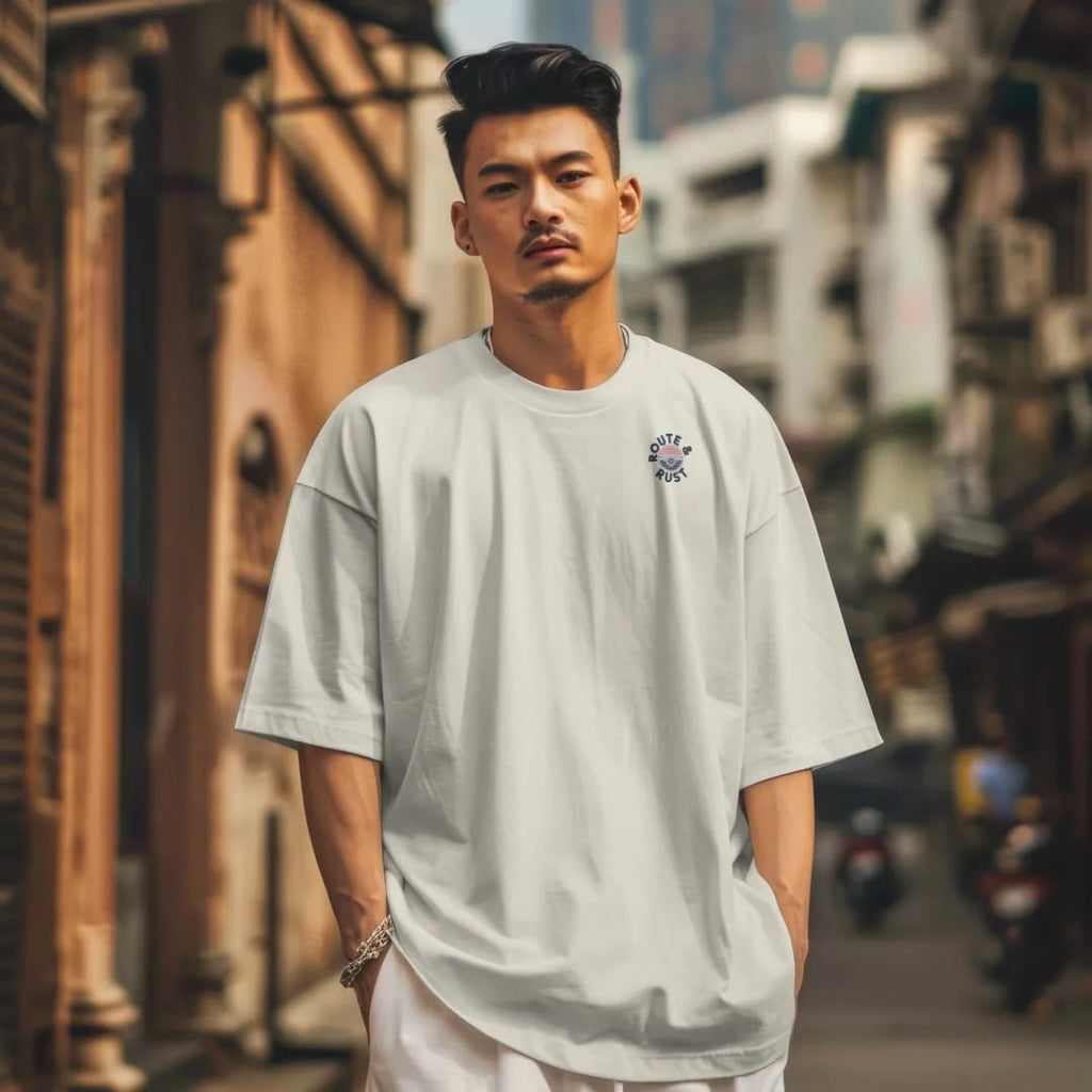 Man in a Ivory tee on a city street, with the small Route & Rust logo on the left chest.