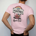 Man wearing a Blossom tee, seen from the back: a roadside produce sign over a basket of ripe peaches, with "FRESH PEACHES" and "NEXT EXIT" in chunky 70s lettering and brush script, printed in faded, cracked brown, rust red, mustard and dusty teal…