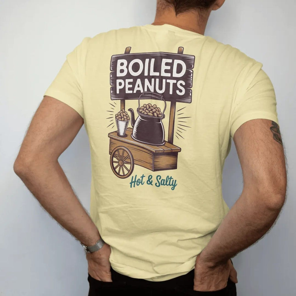Man wearing a Butter tee, seen from the back: a steaming kettle of boiled peanuts on a roadside cart, with "BOILED PEANUTS" and "HOT & SALTY" in chunky 70s lettering and brush script, printed in faded, cracked brown, rust red, mustard and dusty…