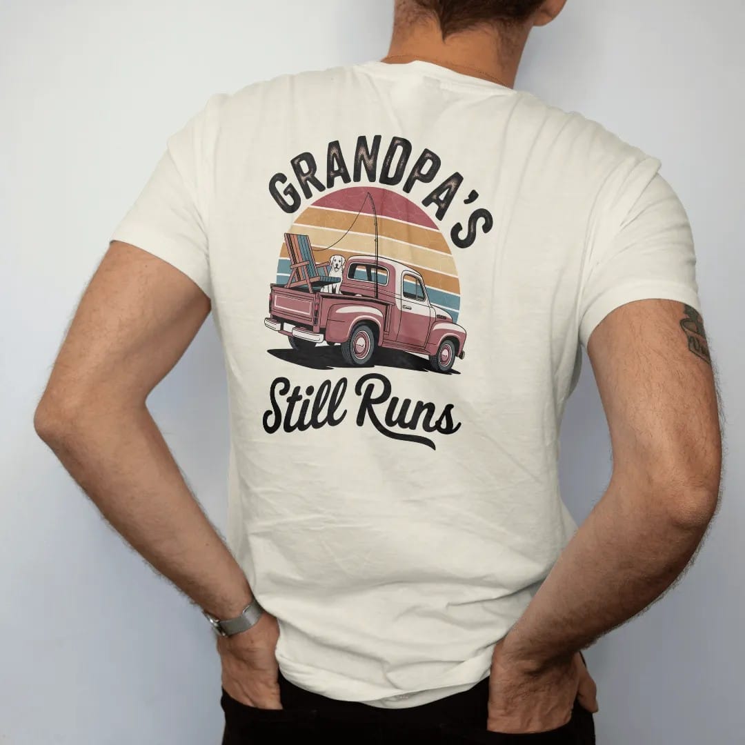 Man wearing a Ivory tee, seen from the back: a vintage pickup with a dog, fishing rod and lawn chair, with "GRANDPA'S TRUCK" and "STILL RUNS" in chunky 70s lettering and brush script, printed in faded, cracked brown, rust red, mustard and dusty…