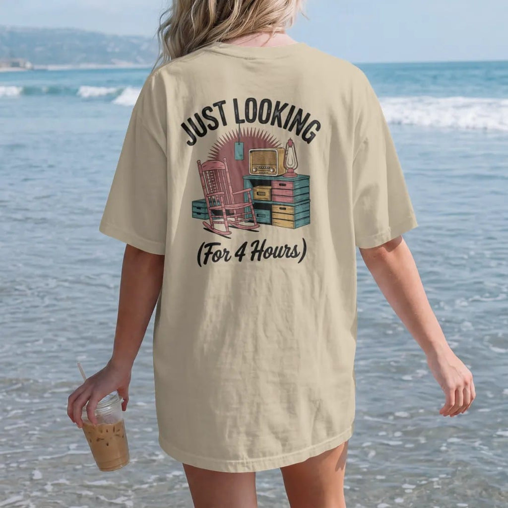Woman on the beach in a Sandstone tee, back view: a cluttered antique booth with a rocking chair, old radio and oil lamp, with "JUST LOOKING" and "(FOR 4 HOURS)" in chunky 70s lettering and brush script, printed in faded, cracked brown, rust red,…