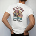 Man wearing a White tee, seen from the back: a triple-scoop cone in front of a walk-up ice cream stand, with "SCOOPS" and "HAND DIPPED" in chunky 70s lettering and brush script, printed in faded, cracked brown, rust red, mustard and dusty teal over…