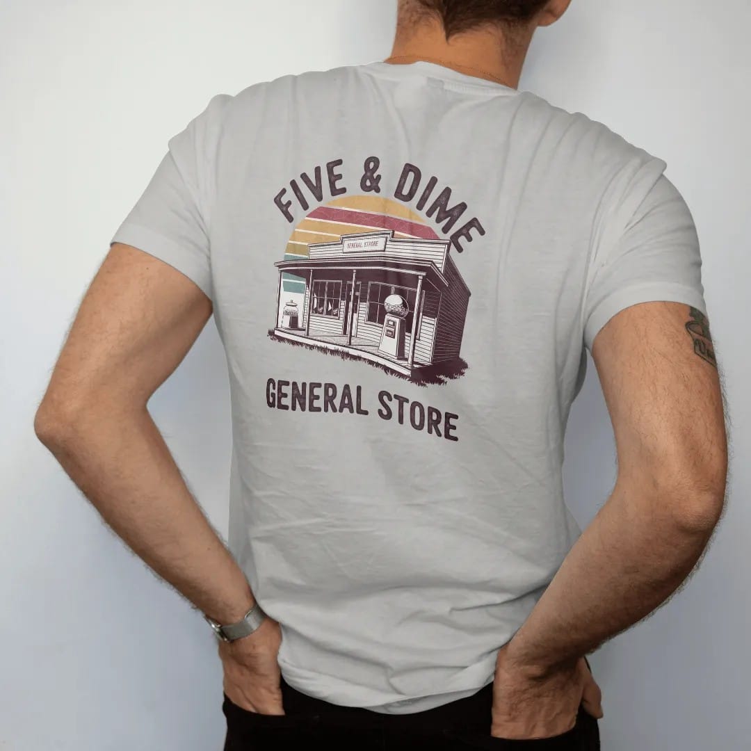 Man wearing a Granite tee, seen from the back: an old general store facade with a candy jar and gumball machine, with "FIVE & DIME" and "GENERAL STORE" in chunky 70s lettering and small 70s caps, printed in faded, cracked brown, rust red, mustard…
