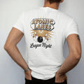 Man wearing a White tee, seen from the back: a googie-style bowling alley sign with a ball smashing pins, with "ATOMIC LANES" and "LEAGUE NIGHT" in chunky 70s lettering and brush script, printed in faded, cracked cream, mustard, burnt orange and…