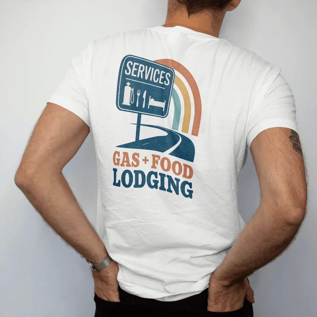 Man wearing a White tee, seen from the back: a highway services sign with pump, fork-and-knife and bed icons at sunset, with "GAS · FOOD · LODGING" in chunky 70s lettering, printed in faded, cracked cream, mustard, burnt orange and dusty teal over…