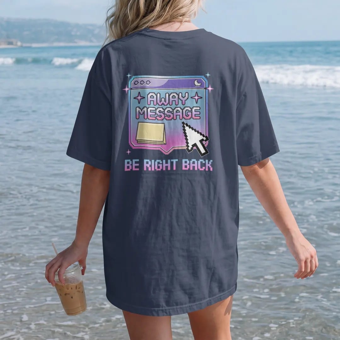 Woman on the beach in a Navy tee, back view: a beveled pop-up chat window with a sticky note and sleeping moon, with "AWAY MESSAGE" and "BE RIGHT BACK" in liquid-chrome bubble letters and small pixel type, printed in glossy gunmetal chrome, cobalt,…
