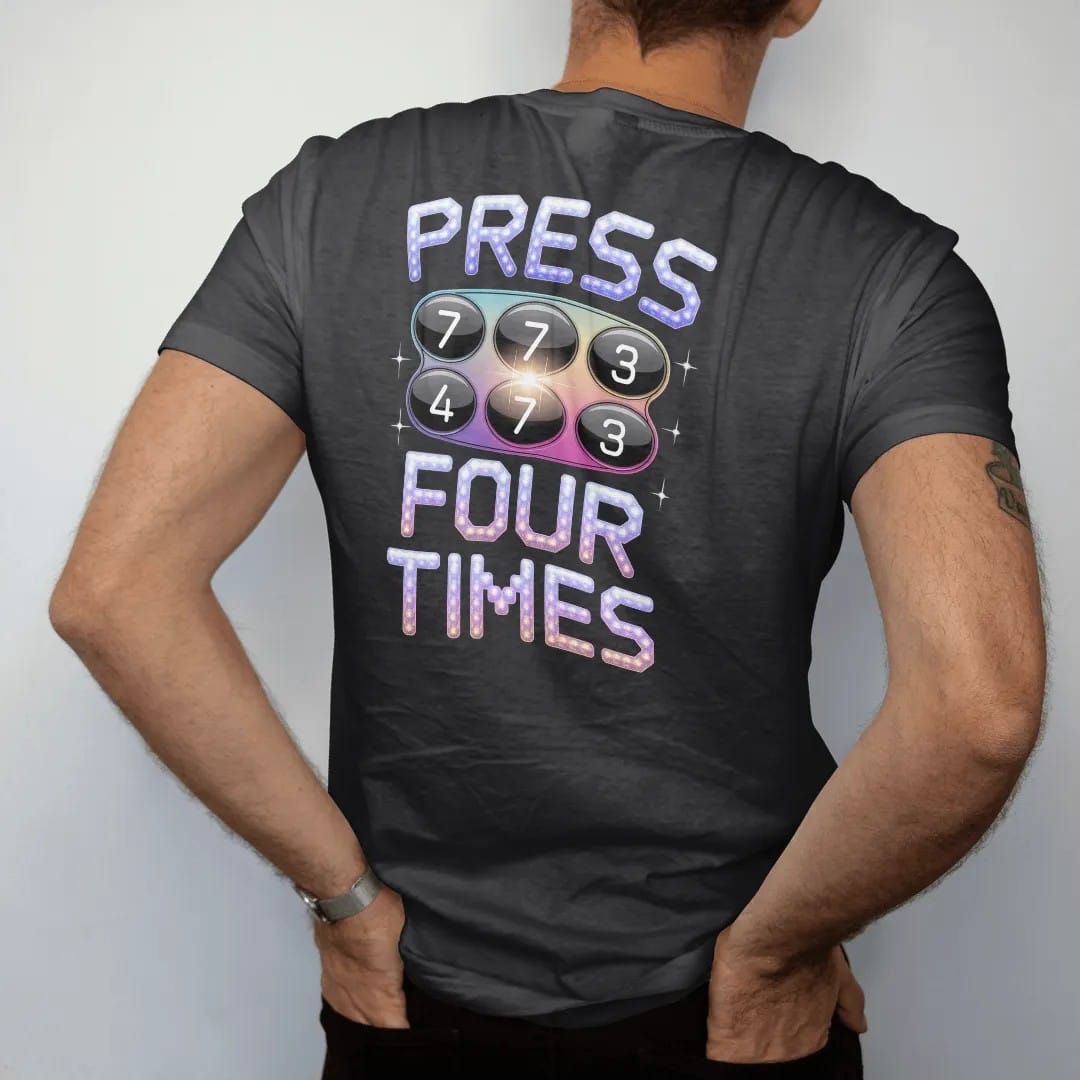 Man wearing a Black tee, seen from the back: a chunky phone keypad with the seven key glowing, with "PRESS 7" and "FOUR TIMES" in liquid-chrome bubble letters and small pixel type, printed in glossy gunmetal chrome, cobalt, hot magenta and violet…