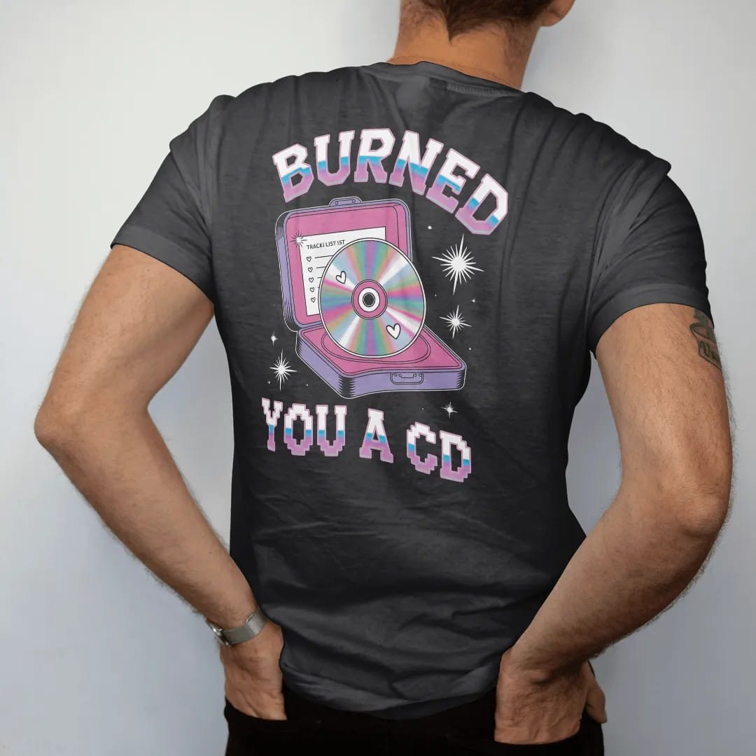 Man wearing a Black tee, seen from the back: a rainbow-sheen disc in a cracked jewel case with a handwritten list, with "BURNED" and "YOU A CD" in liquid-chrome bubble letters and small pixel type, printed in glossy gunmetal chrome, cobalt, hot…