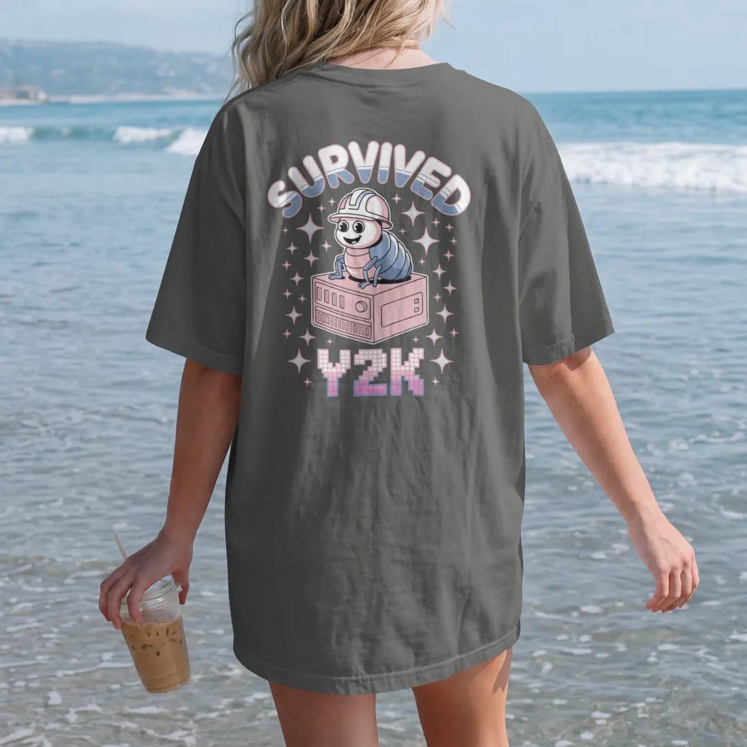 Woman on the beach in a Pepper tee, back view: a cartoon computer bug in a hard hat on a beige tower, with "SURVIVED" and "Y2K" in liquid-chrome bubble letters and small pixel type, printed in glossy chrome silver, baby blue, bubblegum pink and…
