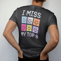 Man wearing a Black tee, seen from the back: a grid of eight pixel smiley photo frames, with "I MISS" and "MY TOP 8" in liquid-chrome bubble letters and small pixel type, printed in glossy gunmetal chrome, cobalt, hot magenta and violet with…